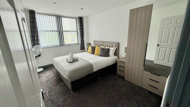 A bedroom with a bed, bedside tables, a mirror, and a wardrobe.