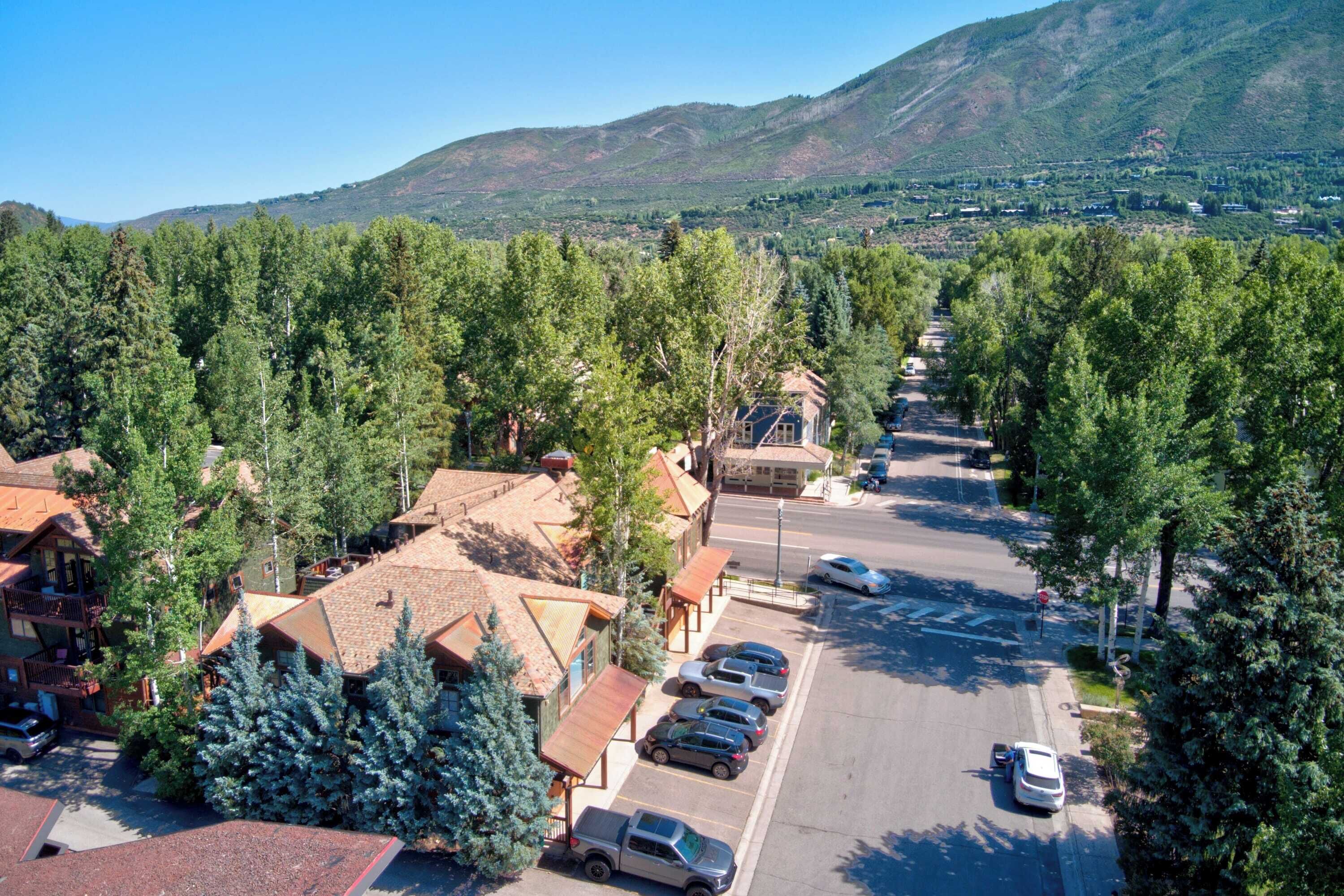 Une ville de montagne dont la rue principale est bordée de voitures garées et d’immeubles aux toits recouverts de tuiles rouges.