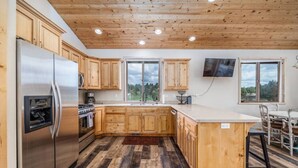Una cocina moderna con armarios de madera, un refrigerador de acero inoxidable y una isla grande.