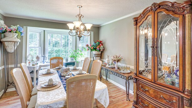 Uma sala de jantar com um armário de madeira, um candelabro e uma mesa posta para refeição.