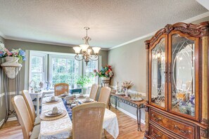 A dining room with a wooden cabinet, a chandelier, and a table set for a meal. - Pool & Tennis Court Access: Home in Warner Robins (Warner Robins)