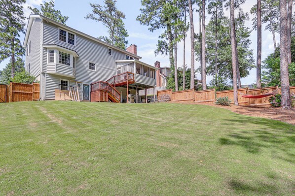 A two-story house with a covered porch and a fenced backyard. - Pool & Tennis Court Access: Home in Warner Robins (Warner Robins)