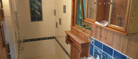 Une salle de bain avec une douche, un lavabo et des meubles en bois.