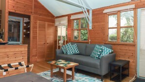 A cozy cabin interior with a sofa, a small table, and a bench. - The Sharpham Boat House (Totnes)
