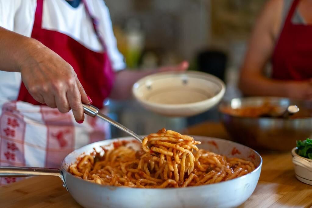 A person cooking spaghetti in a large pan.