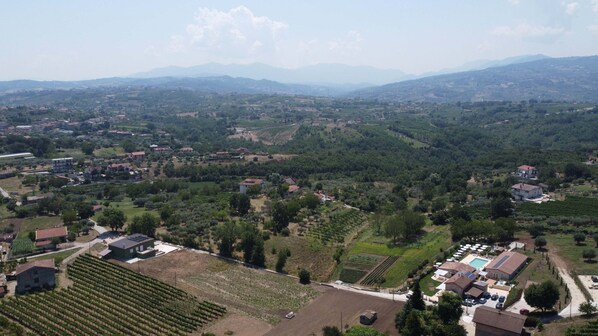 A rural landscape with vineyards, a swimming pool, and residential buildings. - IL POGGIO DEGLI ANTICHI SAPORI (Paternopoli)