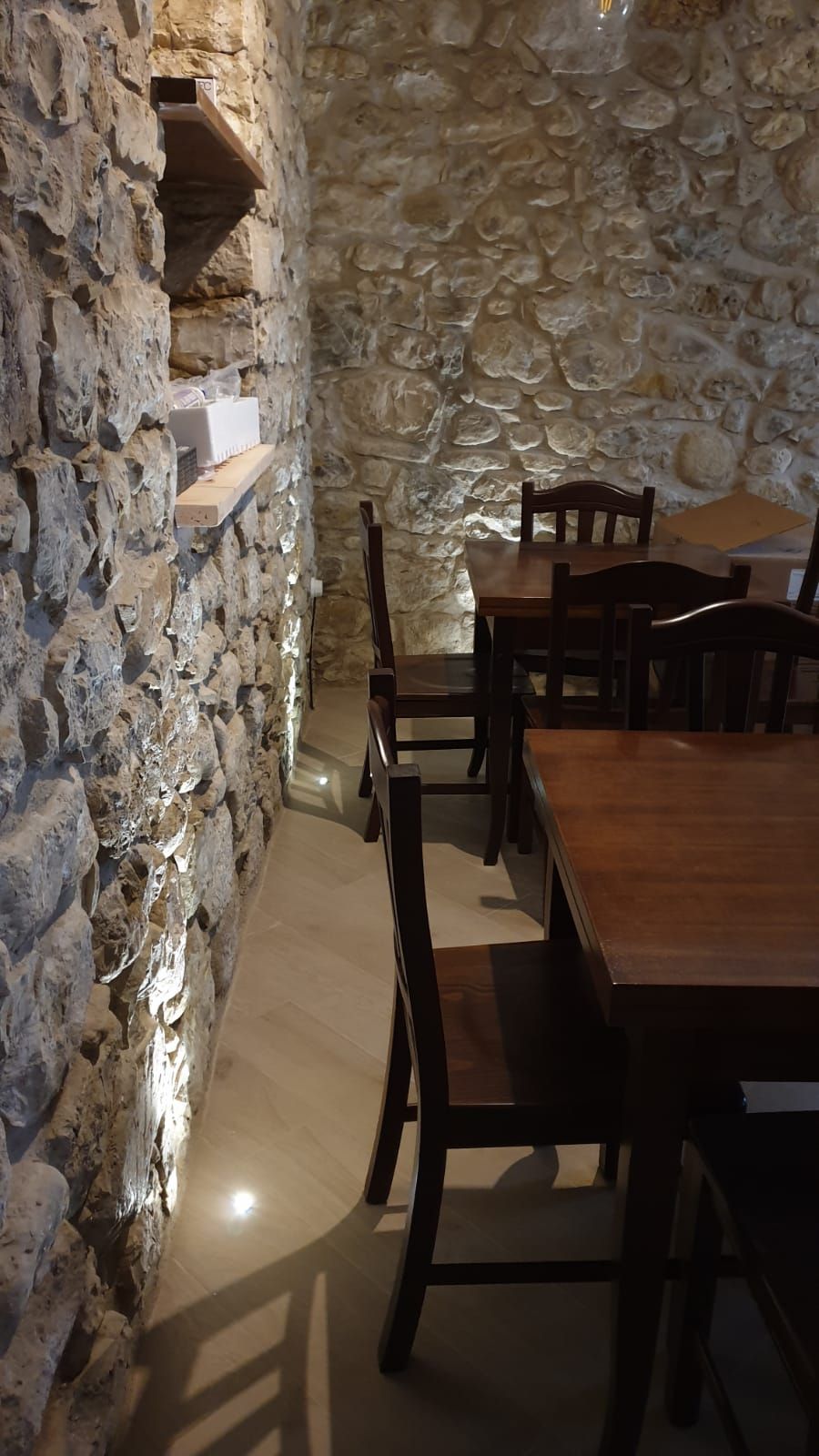 Una stanza con pareti in pietra, un tavolo e sedie in legno.