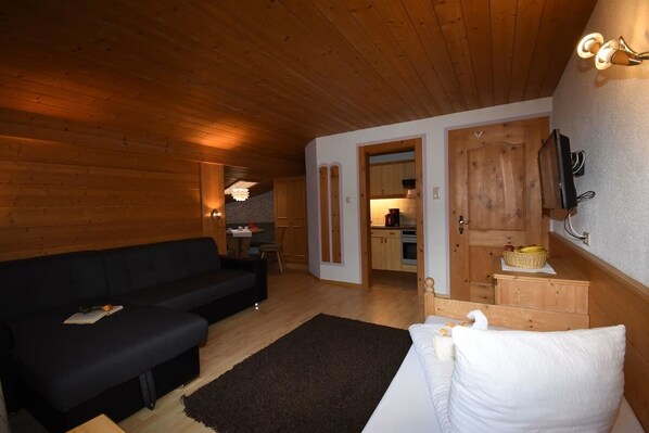 A cozy room with a black sofa, a white bed, and a wooden ceiling.