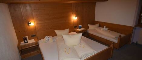 A wooden room with two beds, nightstands, and wall-mounted lights.