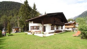 Un chalet traditionnel doté d’un toit à pente, de poutres en bois et d’une pelouse bien entretenue.
