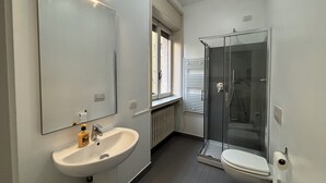 Une salle de bain moderne avec un lavabo blanc, un miroir et une cabine de douche en verre.