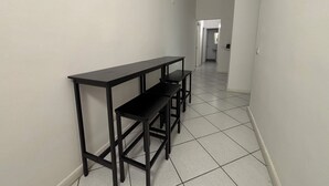 Un couloir étroit avec un bureau en métal noir et deux chaises.