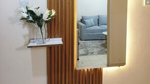 A room with a wooden slat wall panel, a mirror, and a small shelf with a vase of flowers. - one bedroom apartment in juja (Juja)