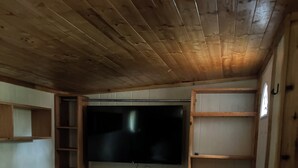 Una habitación acogedora con una amplia televisión de pantalla plana montada en la pared, un sofá oscuro y estanterías de madera.