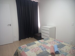 Une chambre à coucher avec un lit, une commode blanche, une porte et un rideau noir.