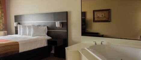 A hotel room with a bed, bedside table, nightstand, and a large mirror.