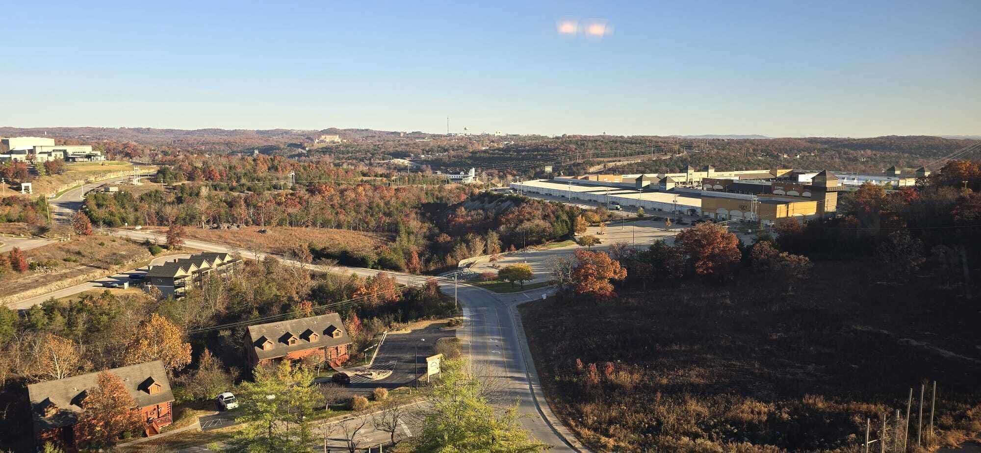 An aerial view of a campus with multiple buildings, roads, and surrounding wooded areas.