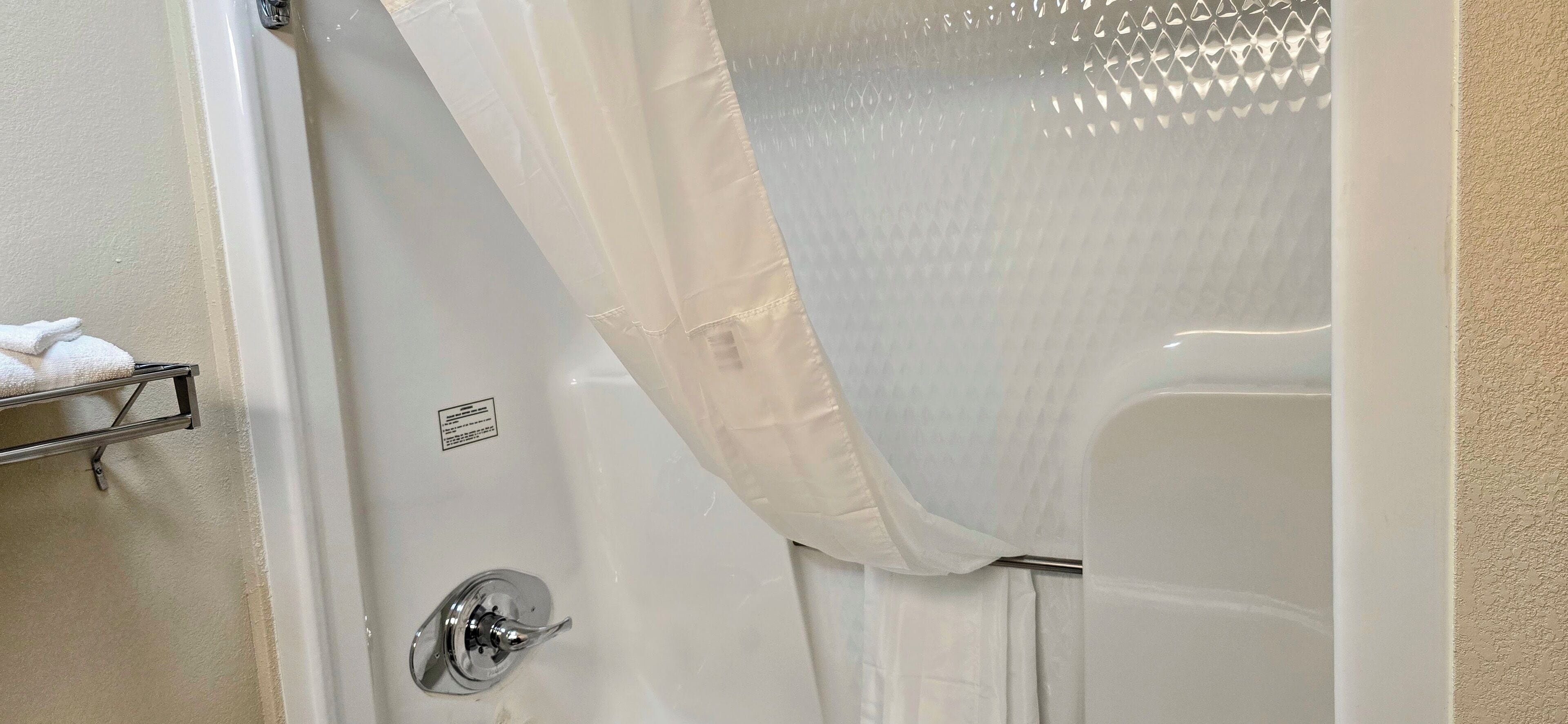 A bathroom with a bathtub, a shower curtain, and a towel rack with a towel.