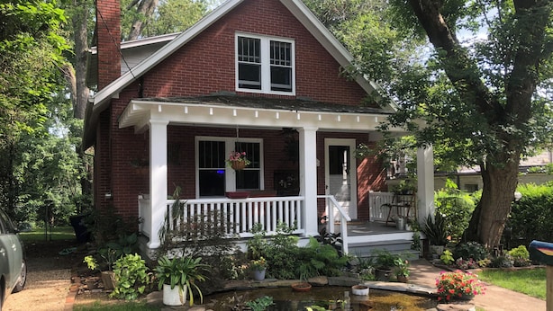 A two-story house with a front porch, a small pond, and a garden with various plants and flowers. - 3-bedroom bungalow very near downtown and walking distance to VT (Blacksburg)