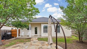 Une maison dotée d’une terrasse en pierre, d’un espace extérieur couvert aménagé en salon et d’un barbecue.