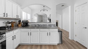 Une cuisine moderne avec des meubles blancs, un plan de travail en marbre et un îlot central.