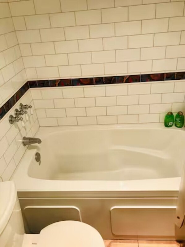 Un baño con una bañera blanca, inodoro y zona de ducha.