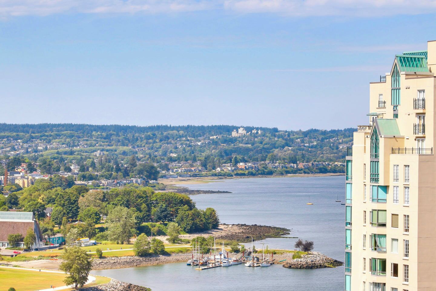 A coastal cityscape with a marina, buildings, and a distant hill.