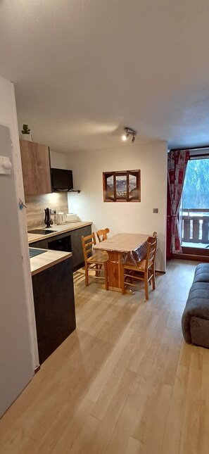 Un espai vital compacte amb cuina, zona de dinar i sofà.
