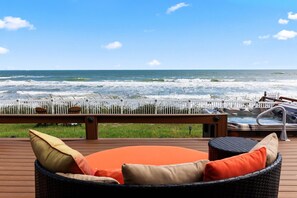 Una terraza de madera con mobiliario exterior, una bañera de hidromasaje y vistas al océano.