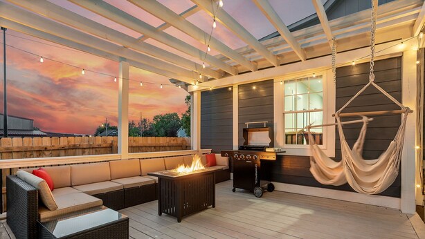 Une terrasse extérieure avec un canapé, un foyer, un barbecue et un hamac.