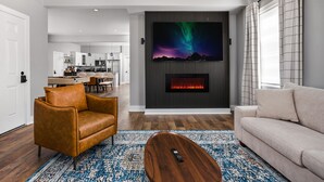 Un salon moderne avec une cheminée, un canapé, une table basse et un mur dédié à la télévision.