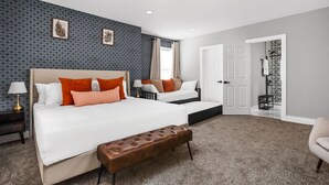 Une chambre d’hôtel moderne avec un grand lit, une banquette, une table de chevet et une vue sur le couloir.