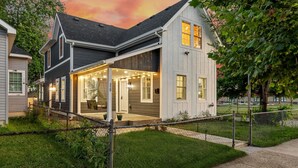 Une maison moderne à deux  étages, dotée d’un porche abrité, d’une cour clôturée et d’une pelouse bien entretenue.