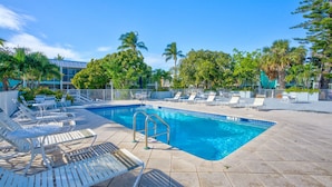 A swimming pool with lounge chairs and a metal railing.