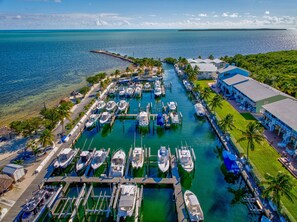 An aerial view of a marina with multiple boats docked, a pier, and a building with a blue roof.