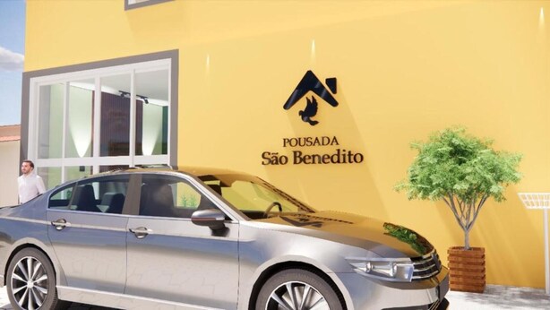 Un coche estacionado frente a un edificio con pared amarilla y un logotipo que dice "POUSADA São Benedito".