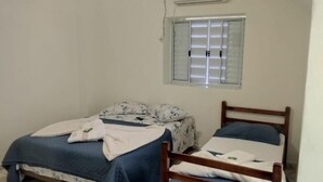 Una habitación pequeña y limpia con una cama individual, una silla y una ventana con persianas.