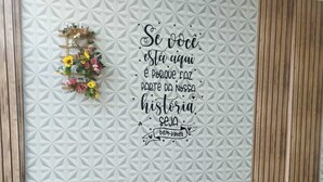 Un rincón cómodo con un sofá y almohadones decorativos, una pared con un patrón geométrico y una frase motivadora.