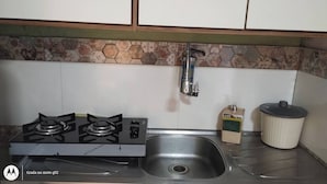 A kitchen with a gas stove, a stainless steel sink, and a tiled backsplash. - Aconchego Volta Redonda 449 (Volta Redonda)