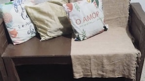A wooden sofa with a beige throw blanket and two decorative pillows. - Aconchego Volta Redonda 449 (Volta Redonda)