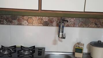 Cozinha com fogão a gás, pia de aço inoxidável e painel de azulejos.