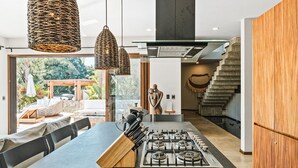 Una cucina moderna con isola centrale, lampade intrecciate a sospensione e vista sull'esterno.