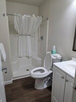 Bañera con ducha, toallas, papel higiénico