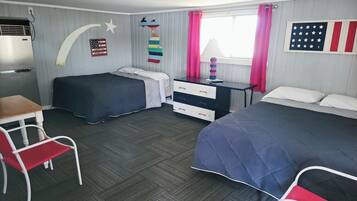 Une chambre avec deux lits, un bureau, une chaise, une commode et une fenêtre avec des rideaux.