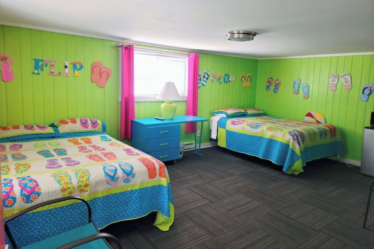 A room with two beds, a desk, and a window with curtains.