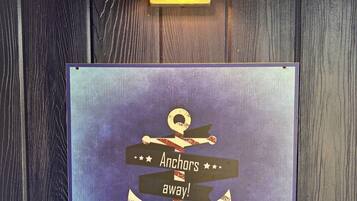 Eine Wandleuchte und ein gerahmtes Schild mit Anker-Design und dem Schriftzug "Anchors away!".