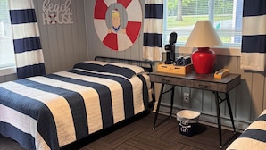 Ein Zimmer mit einem Bett, einem Schreibtisch, einer Lampe und einem Mülleimer.