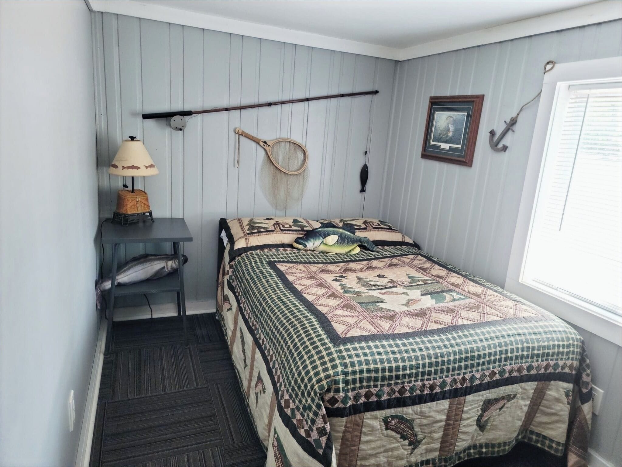Un dormitorio con cama, escritorio, lámpara y ventana.
