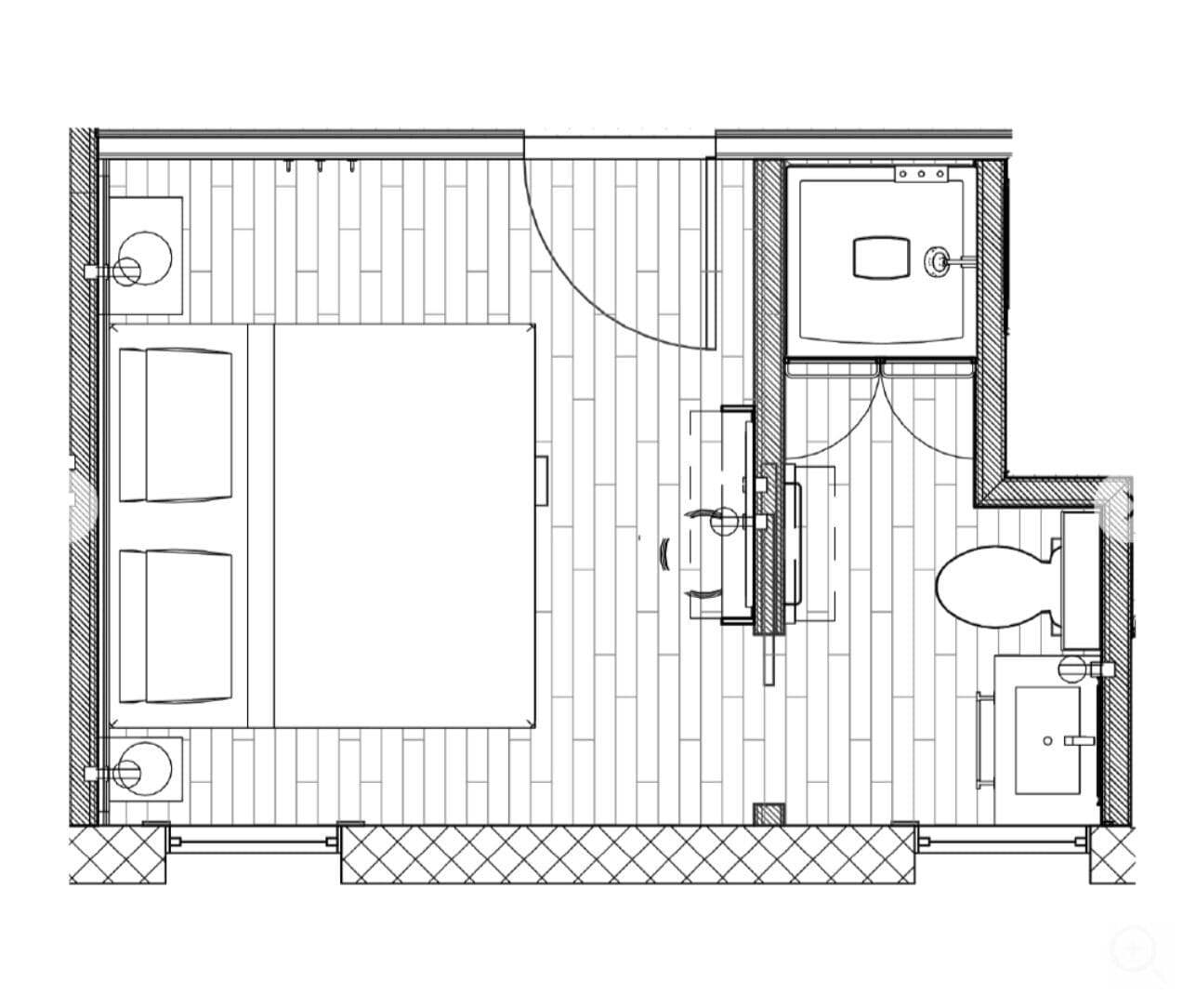 A floor plan of a hotel room with a large bed, a small bathroom, a seating area, and a separate toilet.