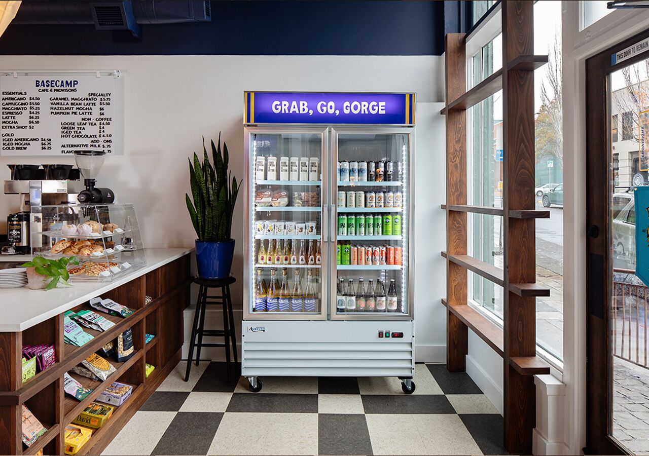 A cafe with a menu board, a beverage dispenser, and a variety of snacks and drinks.